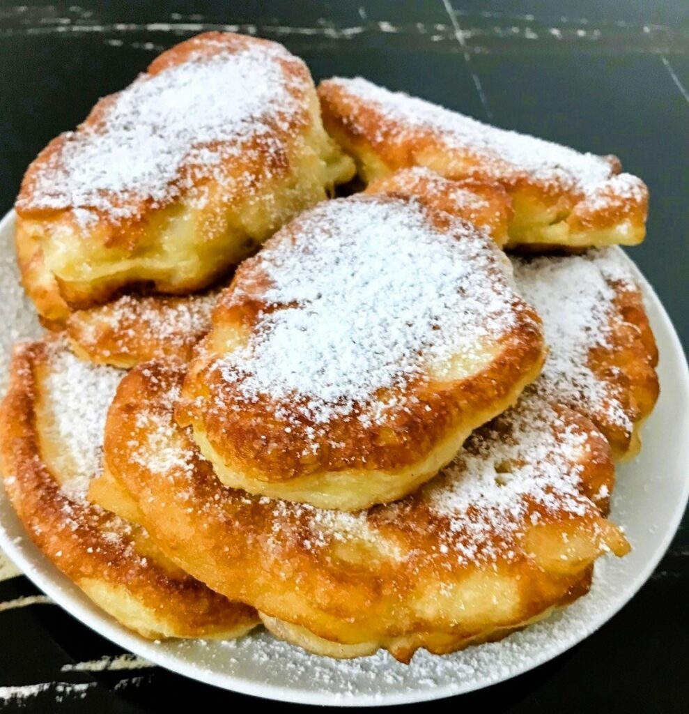 Racuchy drożdżowe na okrągłym, białym talerzu.